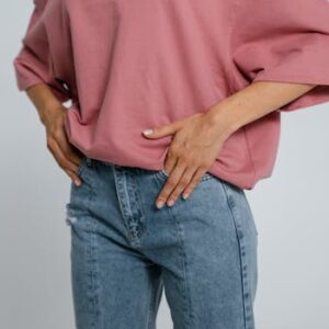 Stylish outfit featuring a pink oversized t-shirt and blue denim jeans in a studio setting.